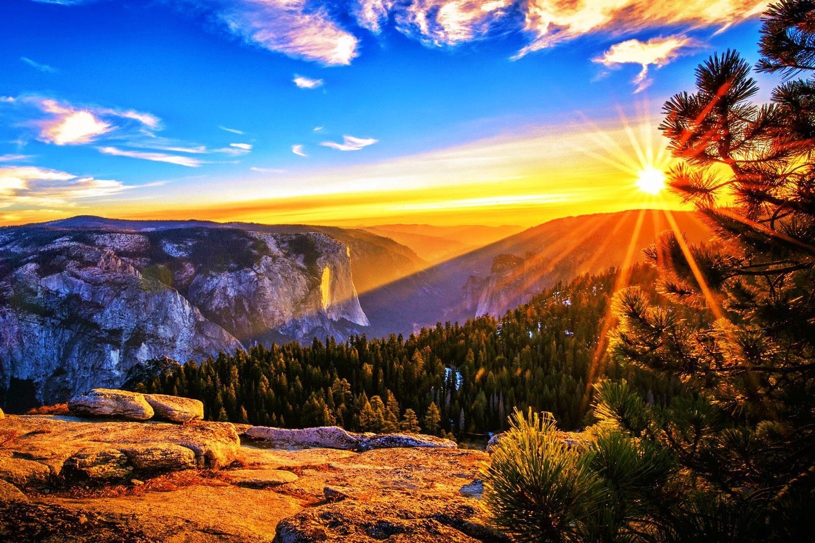 a mountain landscape with a bright sun in the background, with visible rays shining across the rocky and tree-filled foreground